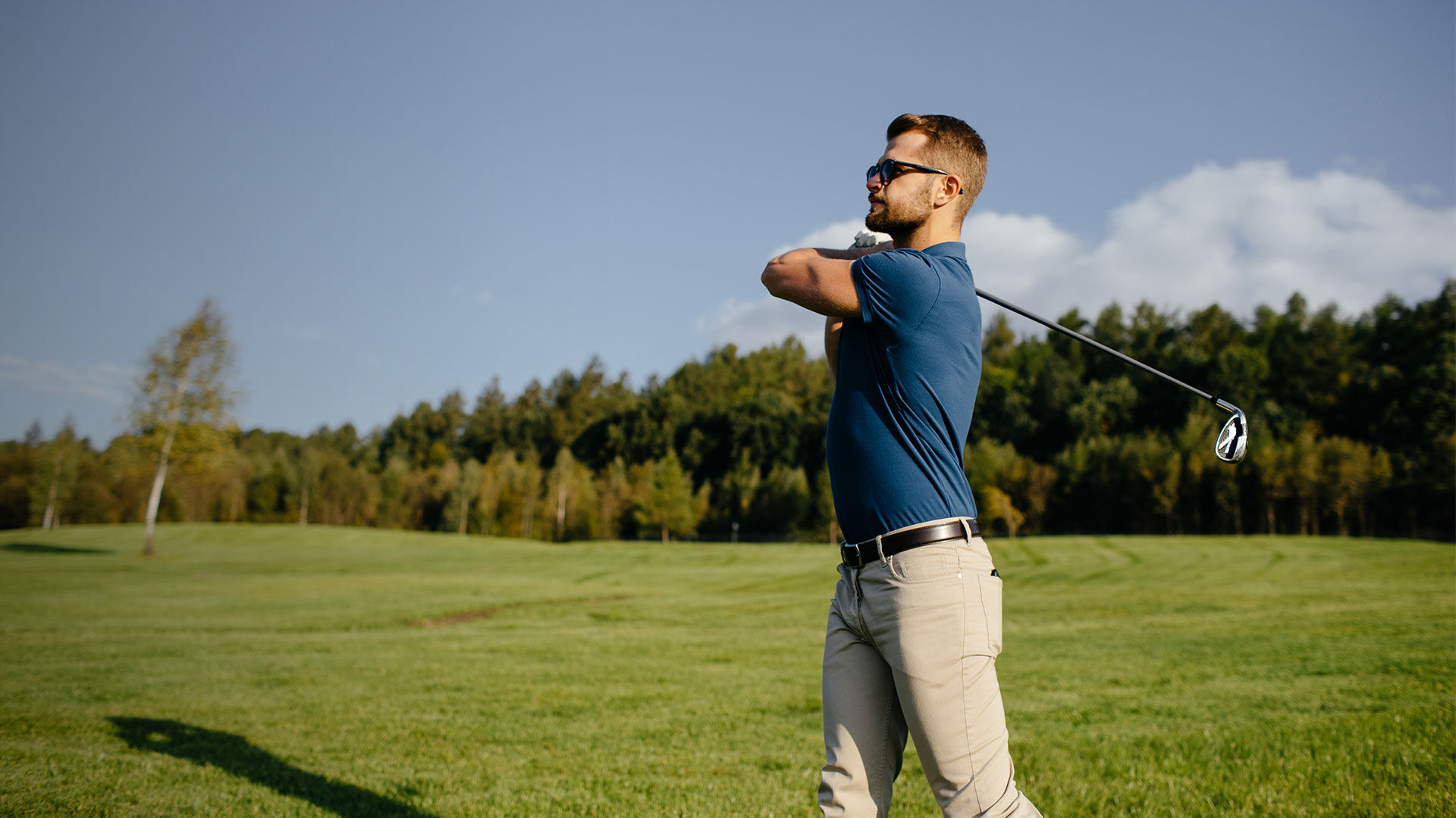 Mies golfaamassa, kasvoillaan golf-aurinkolasit, jotka parantavat n&auml;kyvyytt&auml; kauas ja l&auml;helle